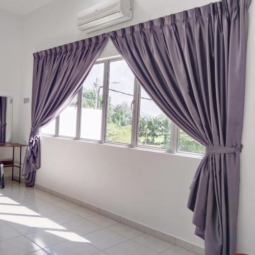 a window with purple curtains in a room at Happpy Impiana Guest House in Bentong