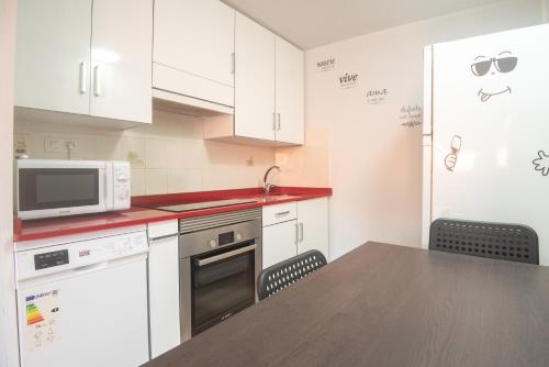 eine Küche mit weißen Schränken und einem Tisch mit einer Mikrowelle in der Unterkunft Solpor de Pedras Negras in San Vicente do Mar