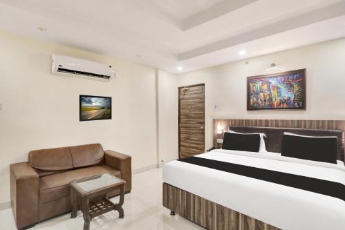 a bedroom with a bed and a chair at Super Townhouse Kankarbagh Formerly Kunwar Alcajars in Patna