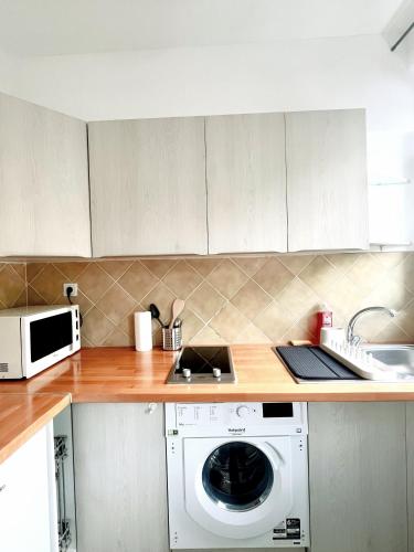 une cuisine avec un lave-linge et un micro-ondes dans l'établissement Center Paris 2 Bedrooms Flat Ideal for sightseeing, à Saint-Mandé