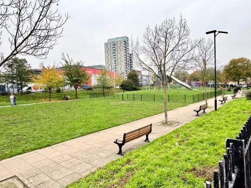 ロンドンにあるStylish 2Bedrooms 2Baths, Balcony Views, Stratford, ABBAの建物のある公園内のベンチのある公園