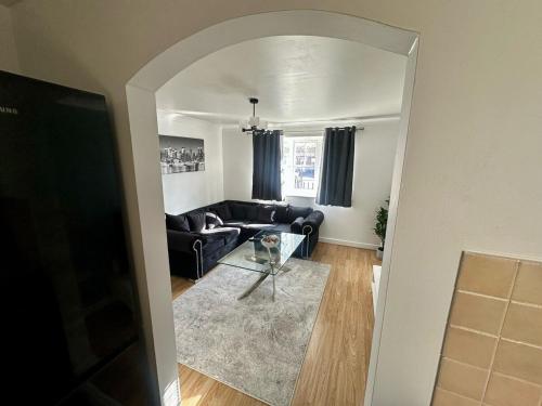 a living room with a black couch and a glass table at Sianavi Apartments - Caspian Way, Purfleet in Purfleet