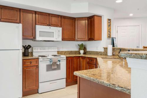 a kitchen with white appliances and wooden cabinets at Lake It Easy - Condo for 7 in Kimberling City