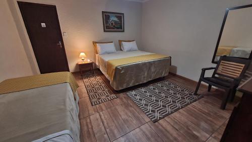 a small bedroom with a bed and a chair at HOTEL ESTÂNCIA - ESTACIONAMENTO GRATUITO ROTATIVO - Vagas Limitadas in Poços de Caldas