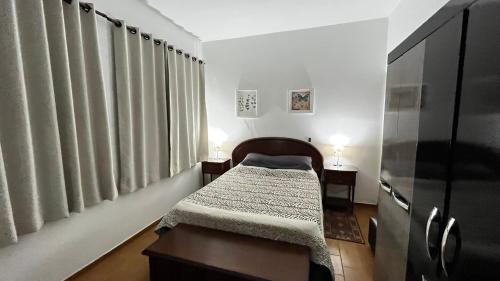 a small bedroom with a bed and two lamps at Casa Rosário Centro de Amparo in Amparo