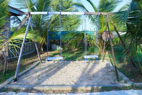 a swing set on a beach with palm trees at NMK Trinco Holiday Inn in Trincomalee
