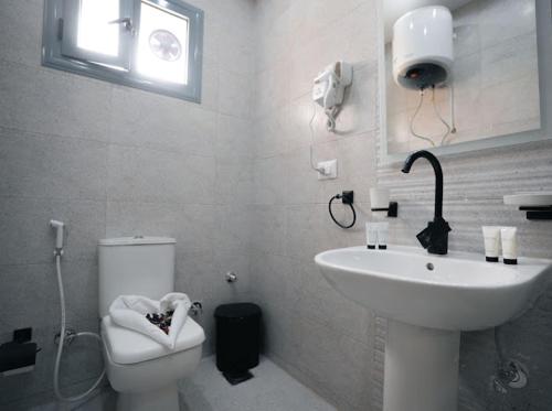 a white bathroom with a toilet and a sink at Tuya pyramids hotel in Cairo