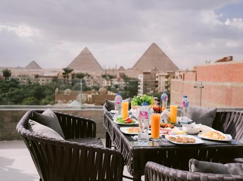 a table with plates of food on a balcony with pyramids at Tuya pyramids hotel in Cairo