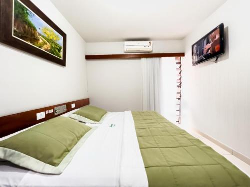 a bedroom with a bed and a tv on the wall at Hotel Damen in Foz do Iguaçu