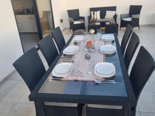 a dining table with plates and glasses on it at Seafront Penthouse with Large Terrace and Panoramic Views-Mellieha Bay Ghadira in Mellieħa