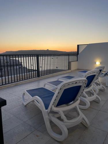 a group of lawn chairs sitting on top of a balcony at Seafront Penthouse with Large Terrace and Panoramic Views-Mellieha Bay Ghadira in Mellieħa
