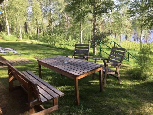 a picnic table and two benches in a park at Hus Bjöksjöblick in Hällefors