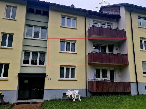 a yellow building with two white chairs in front of it at Holiday Apartment near Triberg Waterfall in Triberg