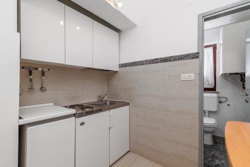 une cuisine blanche avec un évier et des toilettes dans l'établissement Family friendly house with a swimming pool Krnica, Marcana - 24375, à Krnica