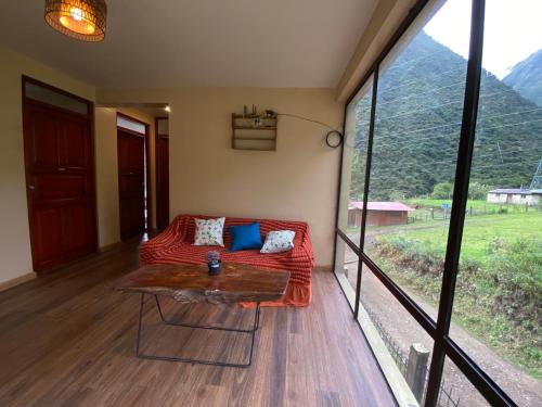 a room with a couch and a table and a large window at Tumi Lodge in Colcapampa
