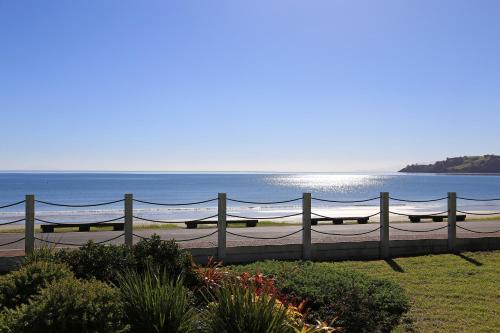a fence in front of the ocean with the ocean behind it at Onetangi Beach Apartments in Onetangi