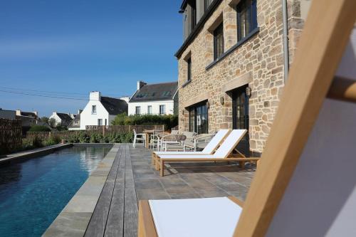 une piscine avec des chaises longues à côté d'un bâtiment dans l'établissement Ti an Aod Beachfront Stone Cottage Sleeps 10 OI Collection Rentals, à La Celle-sous-Gouzon