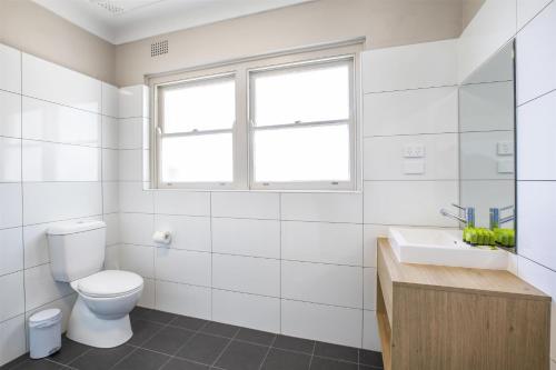 a bathroom with a toilet and a sink and a window at Nightcap at Ocean Beach Hotel in Umina