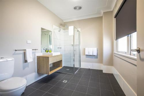 a bathroom with a toilet and a sink and a shower at Nightcap at Ocean Beach Hotel in Umina