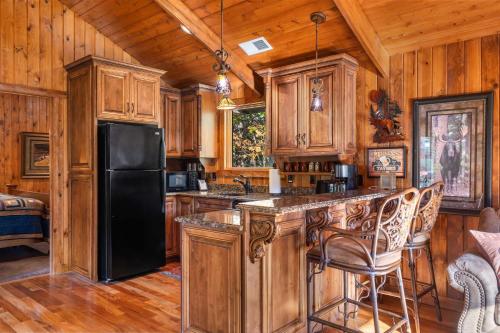 Una cocina con gabinetes de madera y un refrigerador negro. en The Cabin at Rock Canyon, en Branson