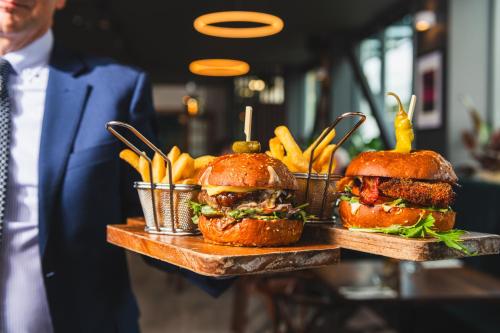 a man holding two plates of sandwiches and french fries at Carnmore Hotel Christchurch in Christchurch