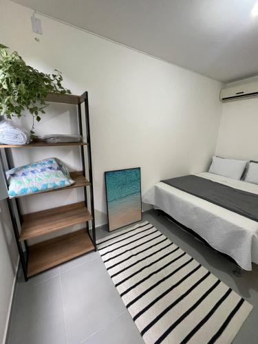 Lindo Apartamento - 600 metros da Praia de Itaparica في فيلا فيلها: غرفة نوم صغيرة مع سرير ورف