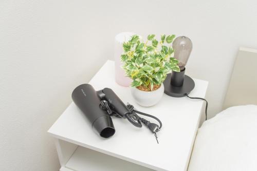 a white table with a phone and a plant on it at Natsuumi ホテル 302高级独栋别墅 独立卫浴 地铁站步行五分钟 成田机场-羽田机场-上野直达 in Tokyo