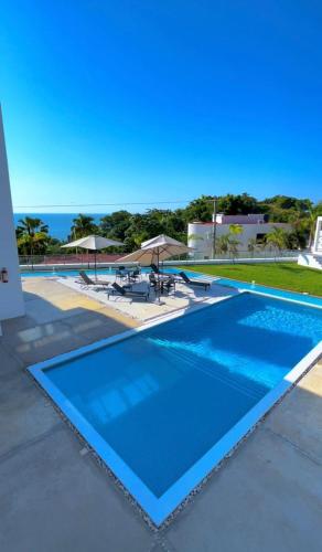 a blue swimming pool with a view of the ocean at Villas Solemar, Aticama in Aticama