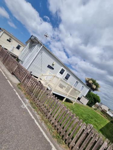 a white house with a fence in front of it at 33 Unity Beach Pet friendly Pets stay free 3 bedrooms sleeps 8 in Brean