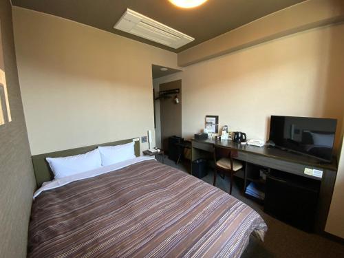 a hotel room with a bed and a desk at Hotel Route-Inn Nakano in Nakano