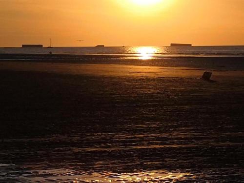 a sunset on a beach with the sun setting at City View Family Retreat in Isigny-sur-Mer