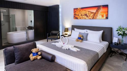 2 ours en peluche assis sur un lit dans une chambre dans l'établissement S Ratchada Leisure Hotel, à Bangkok