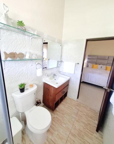 a bathroom with a toilet and a sink and a bed at Bright & Modern Apartment in Puerto Plata, Secure, and Central! in San Felipe de Puerto Plata