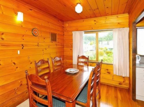 a dining room with a wooden table and chairs at Hosts on the Coast Marine Parade Magic in Cooks Beach