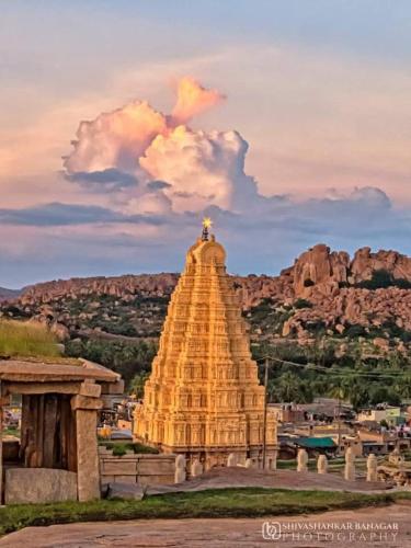 a large yellow stone building with a statue on top at HAREKRISHNA GUESTHOUSE HAMPi in Hampi