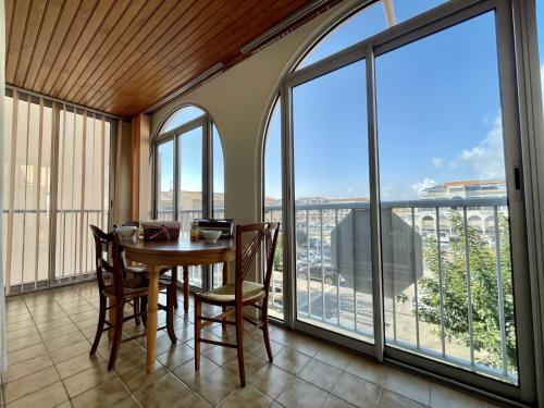 une salle à manger avec une table, des chaises et des fenêtres dans l'établissement Spacieux trois pièces avec loggia vitrée et parking sécurisé - FR-1-338-524, à Sète
