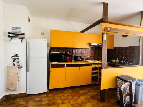 La cuisine est équipée de placards jaunes et d'un réfrigérateur blanc. dans l'établissement Appartement T3 spacieux, parking, 1ère ligne, 30m de la plage - Argelès-Plage - FR-1-309-242, à Argelès-sur-Mer