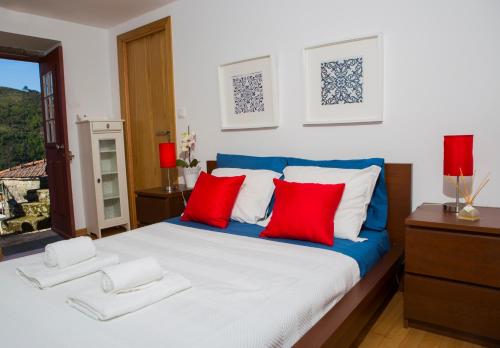 a bedroom with a large bed with red and blue pillows at Casa da Ferreirinha in Sistelo