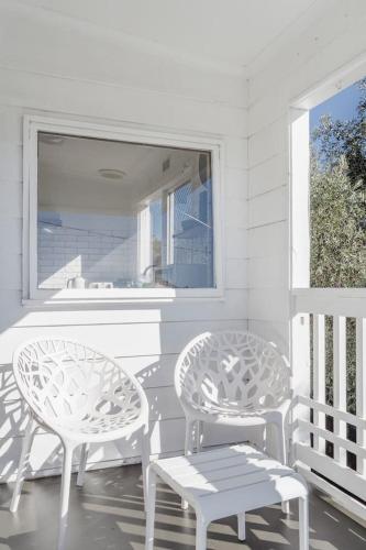 two white chairs and a bench on a porch at Bayview Cottage - Serene Escape between Beach & Bay in Blairgowrie