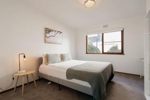 a bedroom with a bed and a table and a window at Bayview Cottage - Serene Escape between Beach & Bay in Blairgowrie