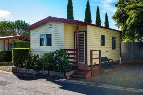 a small yellow house with a porch and stairs at Mount Gambier Central Caravan Park in Mount Gambier
