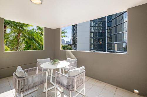a dining room with a table and chairs and two windows at Allegro Apartments in Brisbane
