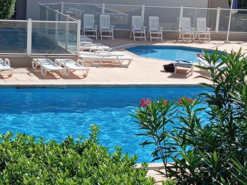 - une piscine avec des chaises longues et de l'eau bleue dans l'établissement Studio cabine avec parking privé, proche plage - FR-1-837-11, à Argelès-sur-Mer