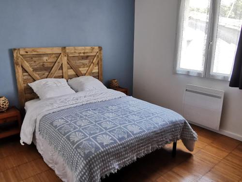 une chambre avec un grand lit avec une tête de lit en bois dans l'établissement Maison rénovée à 400m de la plage du Phare, idéale pour 6 pers. - FR-1-194-297, à La Tranche-sur-Mer