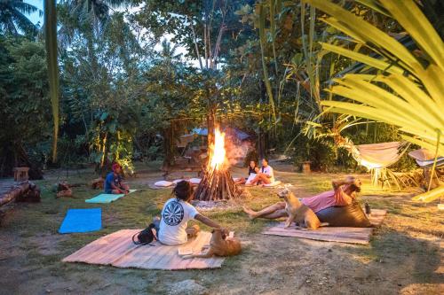a group of people sitting around a fire in the grass at Soffta Surf Ranch in General Luna