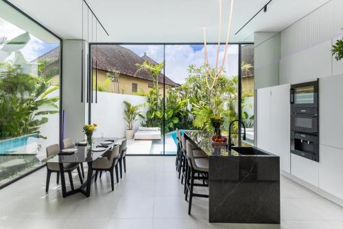 an open kitchen and dining room with large glass windows at Archestet Villas Canggu in Canggu