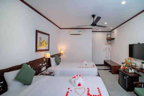 a hotel room with two beds and a flat screen tv at Mayci Boutique Hotel & Restaurant by Amber in Hoi An