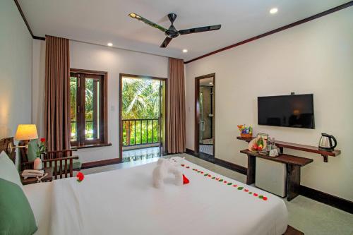 a bedroom with a large white bed and a flat screen tv at Mayci Boutique Hotel & Restaurant by Amber in Hoi An