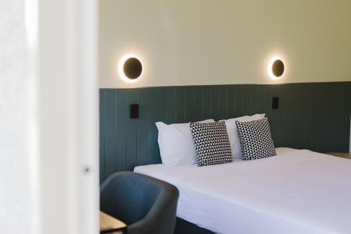a bedroom with a bed and a blue chair at The Heritage Darwin in Darwin