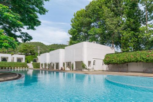 a swimming pool in front of a white building at Villa La Flora Kaeng Krachan in Kaeng Krachan